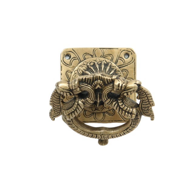 A double Yali door knocker made of brass. Two Yali face away from each other, their tails forming the circular door...
