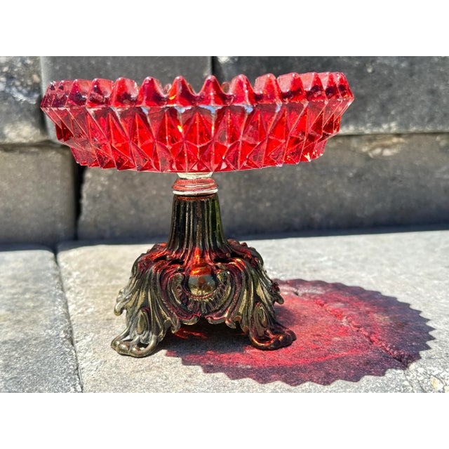Diamond cut glass compote dish. Red glass and brass pedestal base. 5” wide x 4 1/2” tall. Dated 1973 on the bottom.
