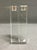 A pair of Oleg Cassini crystal candlesticks featuring a clean modernist design with a squared column and recessed candle...