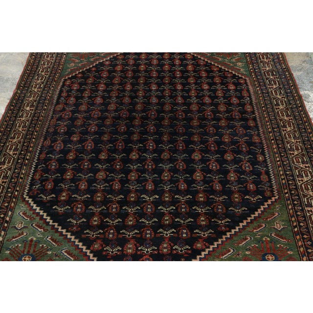Hand-knotted in wool and originating from the storied Hamadan province circa 1950–1960, this 5x8 vintage Persian Malayer...