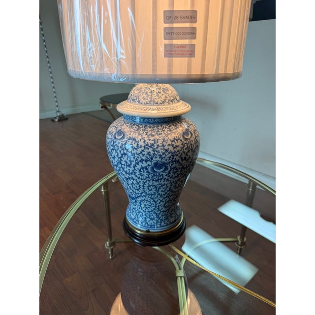 A Haig ginger jar table lamp featuring a blue and white ceramic body with an intricate floral vine and scroll pattern. The...