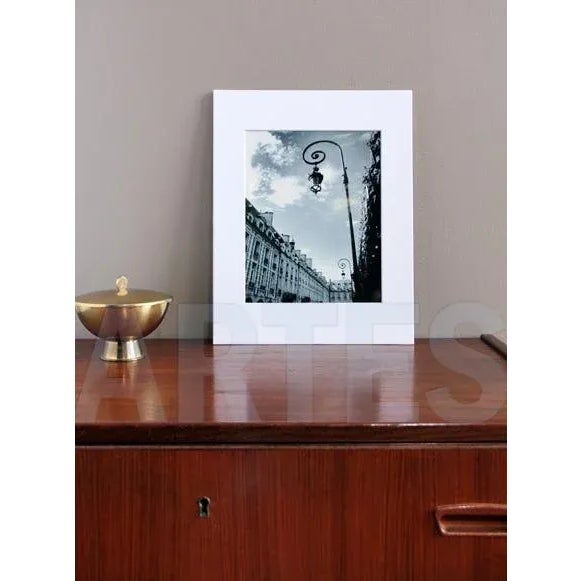 A serene and perspective view of a Paris courtyard in black and white, capturing the architectural beauty and iconic lamp...