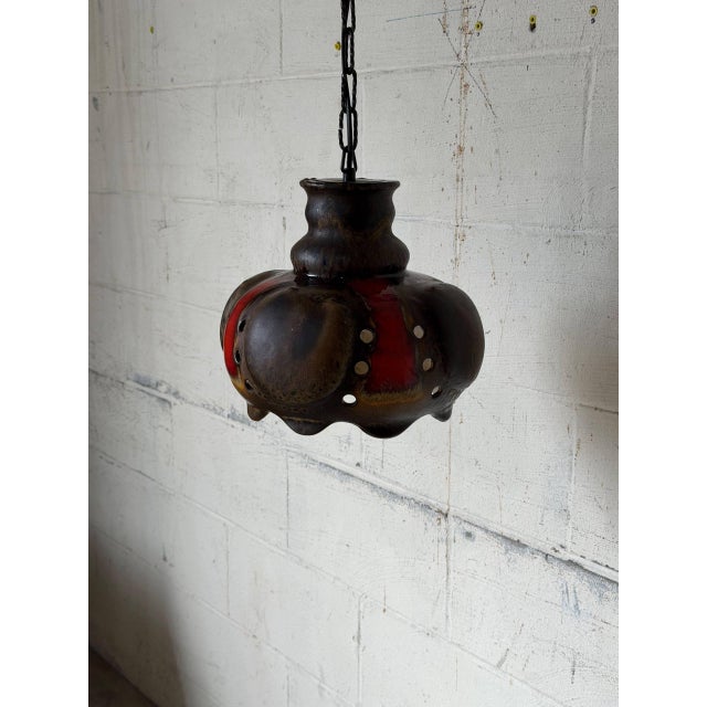 Featuring a bulbous form with decorative circular cutouts along the sides, this hanging light directs illumination...
