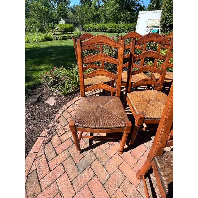 Very handsome characterful set of 10 French Country style walnut ladderback dining chairs with rush seats. Sturdy and...