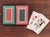 A pair of coordinated playing card decks, printed with an 18th century rug inspired design each in an inverted color...