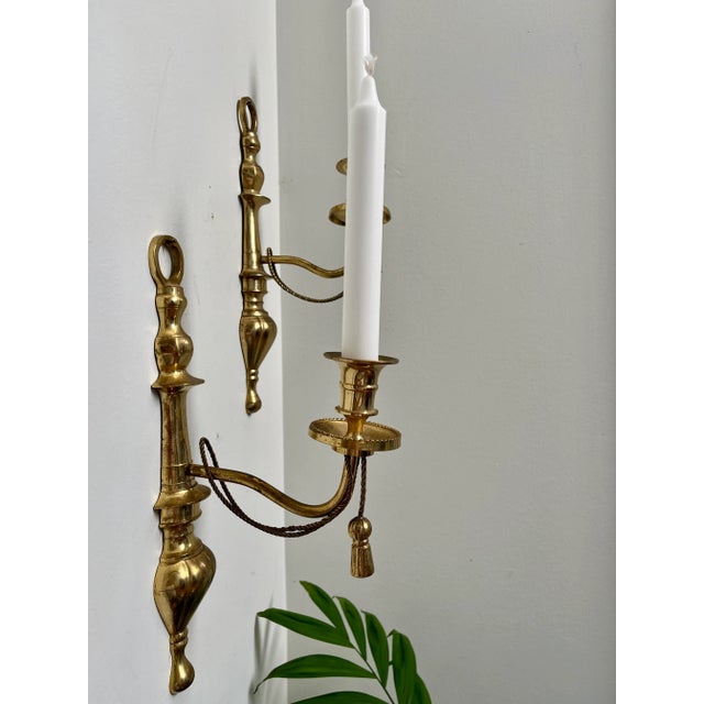 An elegant set of two Italian brass wall sconces dating to the 1980s, featuring refined tassel and swag motifs inspired by...