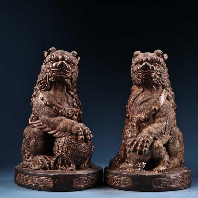 This is a matching pair of cast bronze guardian lion (Foo Dog) figurines, featuring a worn gilt finish over a dark, aged...