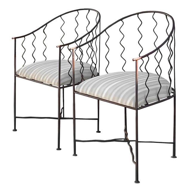 An extremely rare pair of vintage wrought iron French accent side chairs with a striped seat cushion and scalloped/wavy...