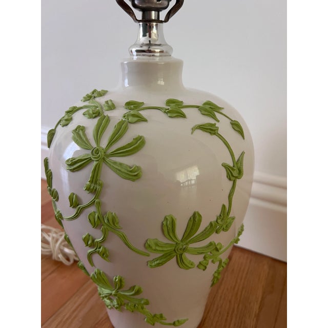 This refined vintage ceramic lamp features a classic urn-shaped body in glossy white glaze, embellished with applied...