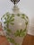 This refined vintage ceramic lamp features a classic urn-shaped body in glossy white glaze, embellished with applied...