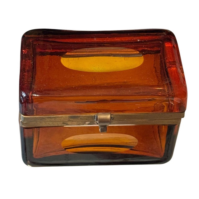 A striking mid century amber art glass casket box featuring richly colored translucent amber glass with distinctive oval...