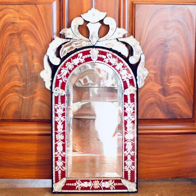 A small mirror with a lot of presence, the red cut to clear arched mirror frame is enhanced by a clear glass crest and...