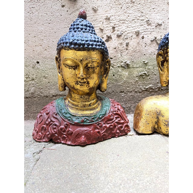 A set of 3 beautiful Iron Buddha busts, painted in a chic gold with royal blue, green and red detailing. The center Buddha...
