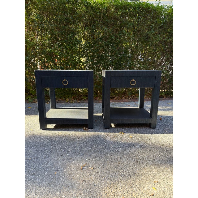 Elegant and modern pair of Serena and Lily Blake 1-Drawer nightstands in navy blue raffia with brass ring pulls. This is a...