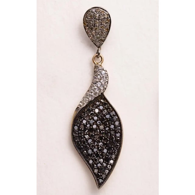 A pair of dangle earrings comprised of black and white diamonds. All are round, brilliant cut diamonds in a pave` setting....