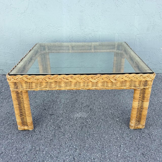 Vintage Boho Chic square coffee table featuring a richly woven natural rattan and wicker frame topped with clear glass....