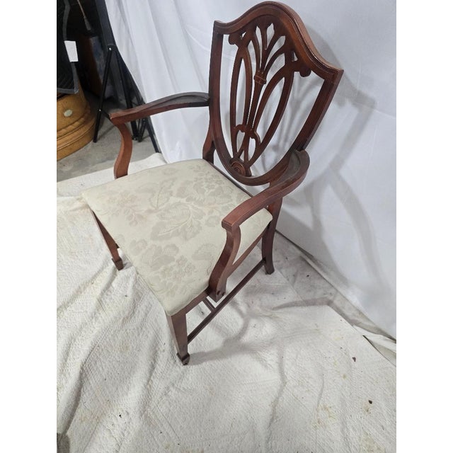A refined Hepplewhite-style armchair showcasing a classic shield-shaped back with intricate pierced splat detailing....