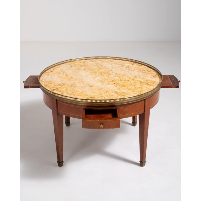 A refined bouillotte table inspired by Louis XVI design, featuring a marble top and brass detailing. Originally used for...
