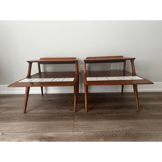 Classic mid-century pair from Lane's Cosmopolitan line. Two-tier walnut construction with splayed legs and brass ring...