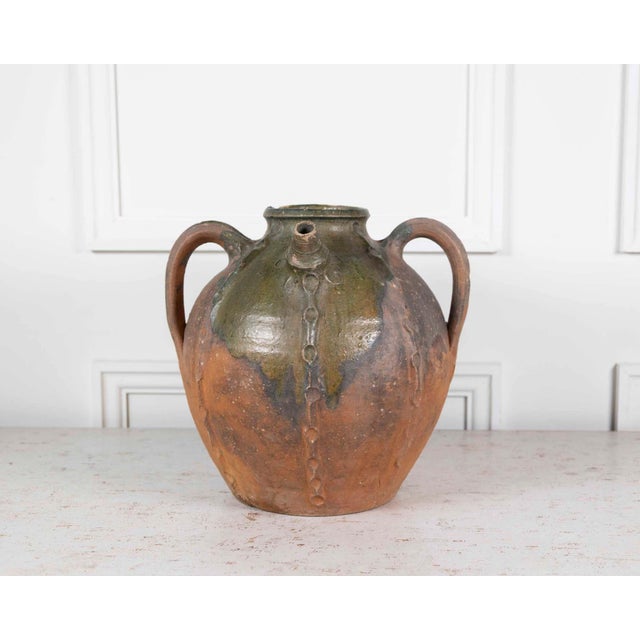 Made in France around 1780, this unglazed earthenware oil pot is decorated with a green splash glaze and impressed...