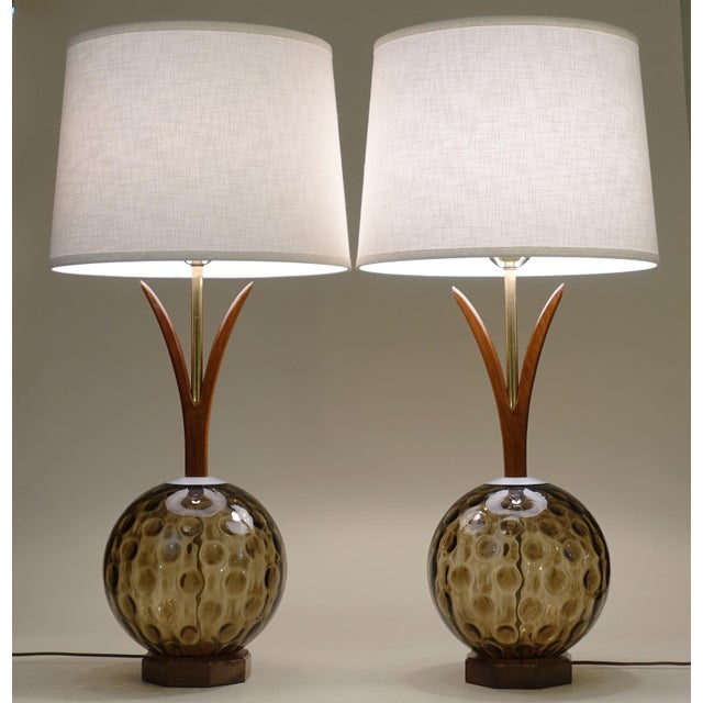 A brilliant and striking pair of Large Mid Century Tiki Modern styled blown Amber colored glass globes with Walnut wood...