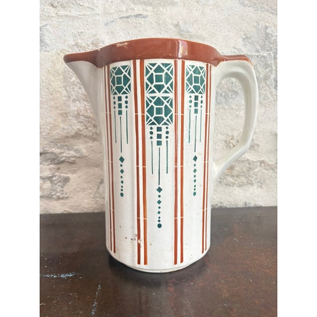 Art Deco faience pitcher made in Saint-Amand-les-Eaux, France. White ground with rust-orange pinstripes and teal-green...
