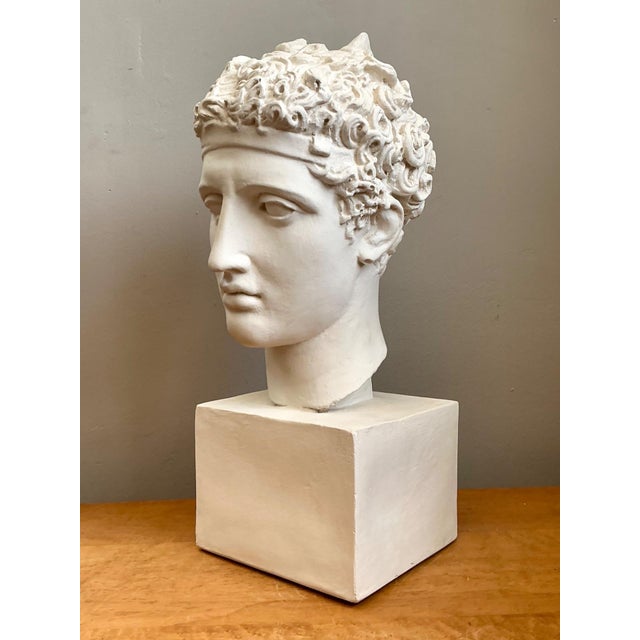 A striking tribute to the enduring beauty of classical antiquity, this vintage plaster bust depicts a noble Roman warrior...