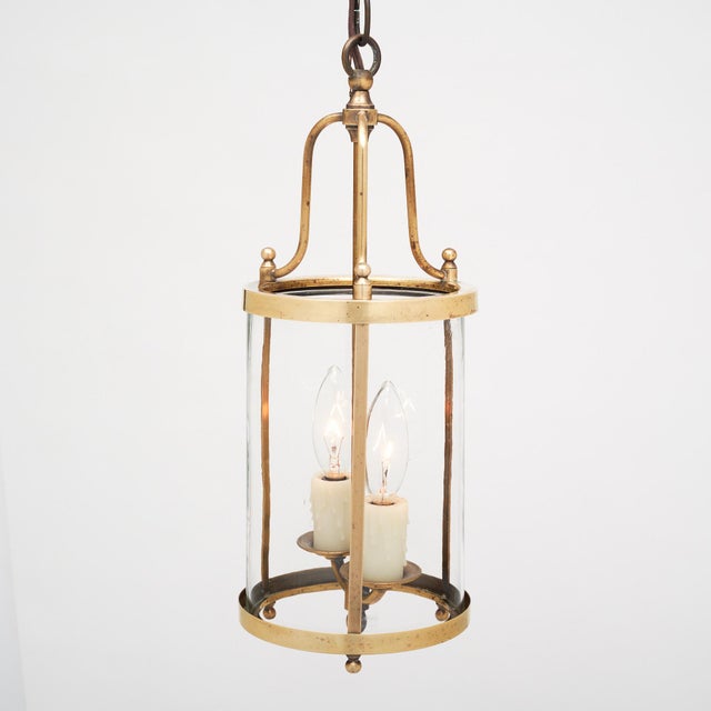 Pair of lanterns from France made with a solid brass structure and curved glass panels. There are two arms with candelabra...