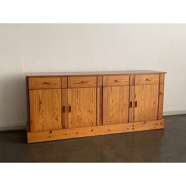 Bold, knotty pine planks define the facade of this commanding modernist sideboard, their swirling organic grain providing...