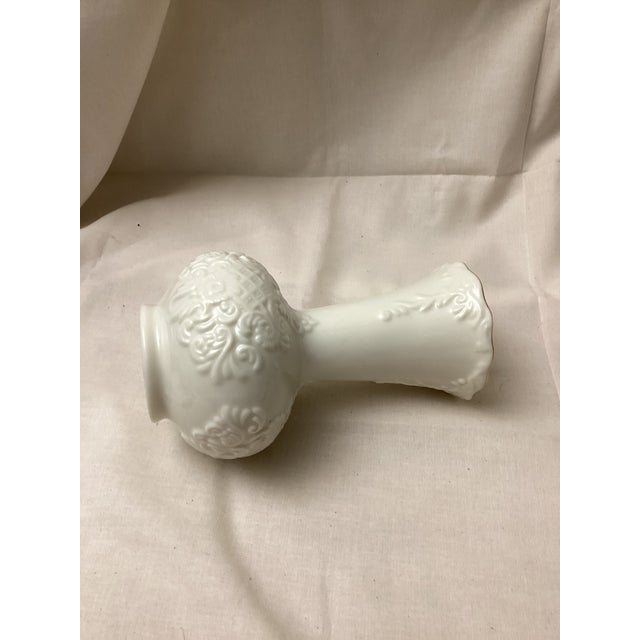 This vase features a classic design with embossed florals or Scalloped, patterns, and a gold trim around the fluted top...