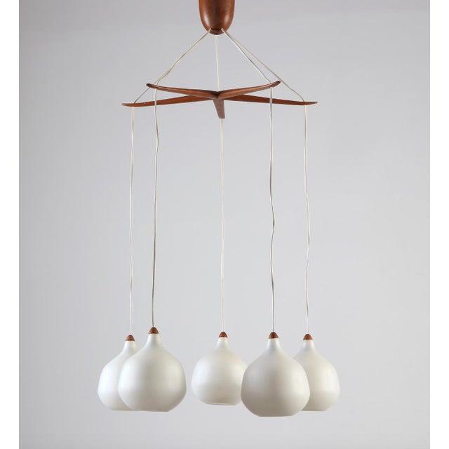 A Lighting pendant by UNO & ÖSTEN KRISTIANSSON. Wood with shades in opaline glass. Produced by Luxus, Vittsjö. Circa...