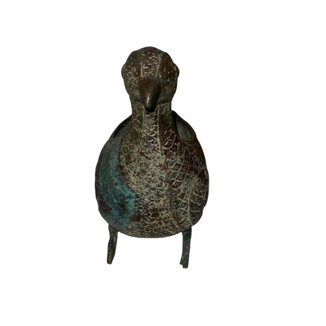 A decorative Chinese archaistic bronze bird-form vessel, modeled as a long-necked bird with a deep hollow body, stylized...
