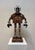 This found object assemblage features a whimsical robot figure, crafted from an eclectic mix of vintage materials,...