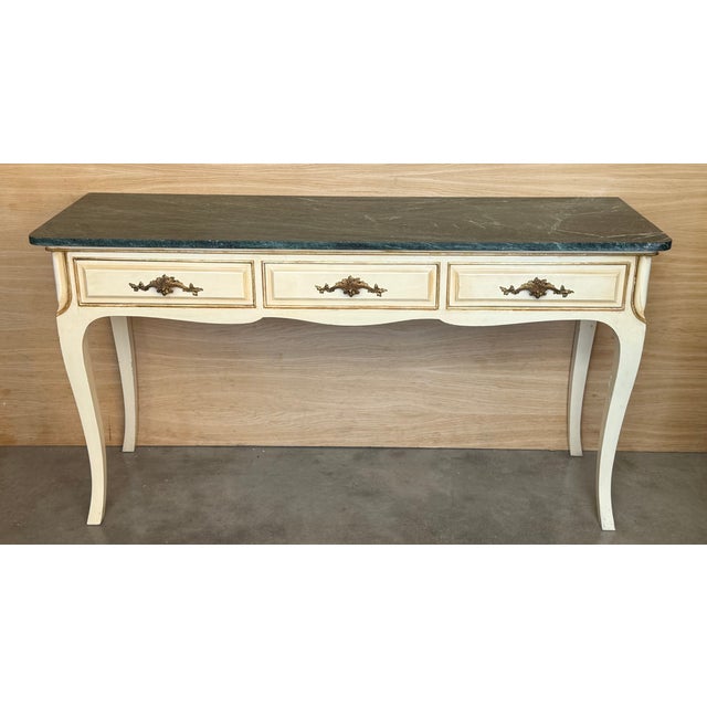 This elegant antique console was created in France, circa 1900. The white painted table sits on tapered legs over a carved...