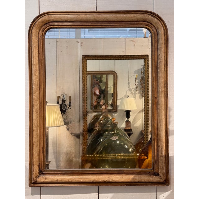 The classic Louis Philippe form with rounded upper corners and a molded giltwood frame showing warm, even patina. A beaded...