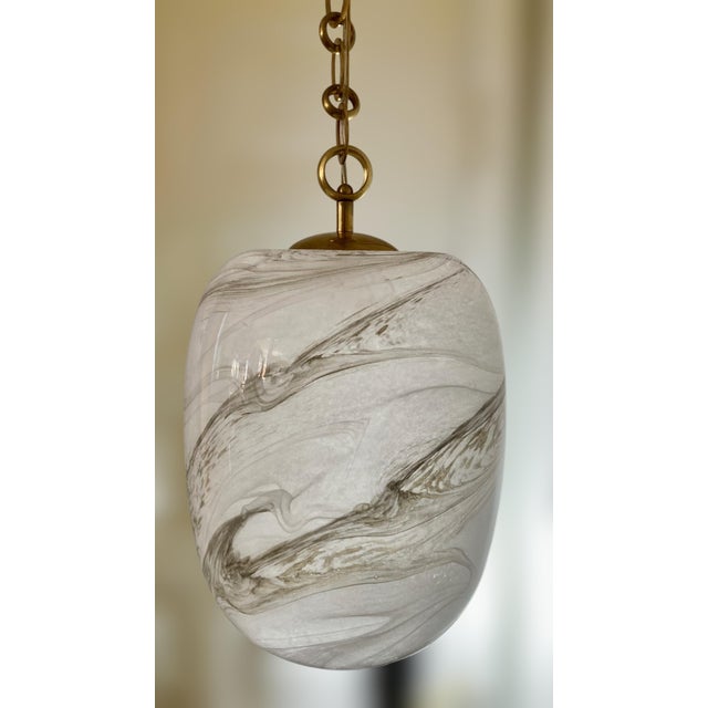 This Italian faux alabaster glass pendant light features a soft, swirling marbleized effect in smoky gray and white tones....