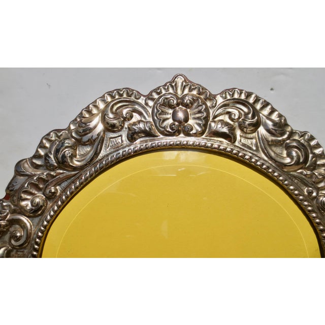 Sterling silver domed top photo frame with a beveled glass cover. Mahogany-backed panel. Domed top with scalloped design...
