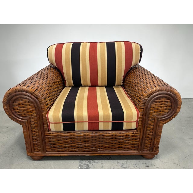 Substantial British Colonial rattan club chair in the style of Ralph Lauren. Features thick handwoven rattan over a fully...