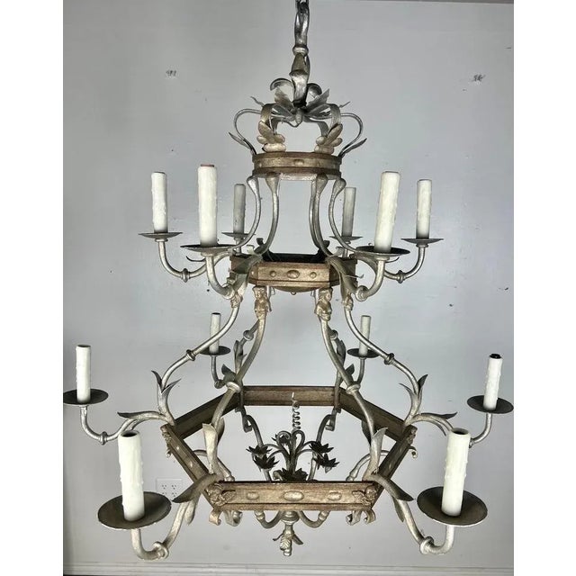 Monumental size 12-light, two-tiered silvered chandelier. The chandelier is adorned with a crown on top and cherub faces...