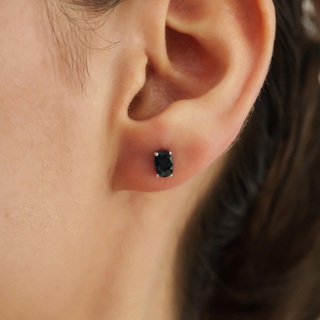 A Pair of Moody Blue Sapphire Oval Solitaire Stud Earrings in 925 Silver - Minimalist Luxe brings understated elegance to...