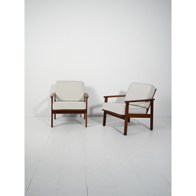 Pair of 1960s Danish armchairs in dark teak: solid structure, wide seat, slightly inclined backrest, and rounded armrests...