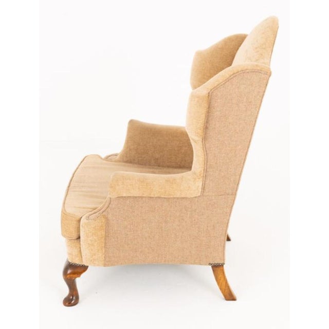 A handsome pair of Georgian-style wing chairs, standing on elegant cabriole front legs with swept rear legs Circa 1920 The...