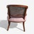 An elegant Regency-style barrel-back armchair crafted in warm stained wood with a wraparound woven cane back and an...