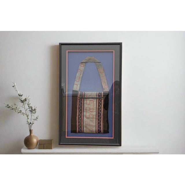 This framed textile offers a poignant glimpse into the cultural traditions of the Hmong people, an ethnic group with a...