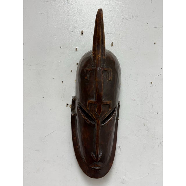 Design Plus Gallery presents a Carved African Wood Mask. This hand carved wall mask presents an elongated face with a...