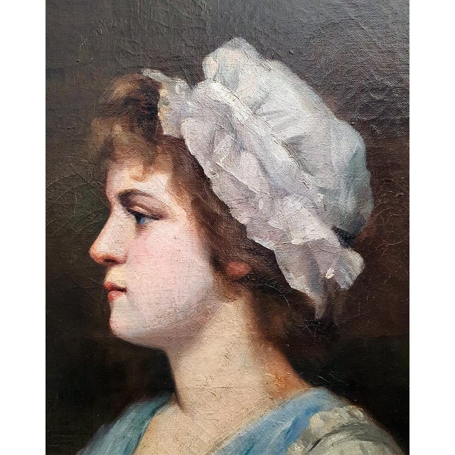 Refined antique oil-on-canvas portrait depicting a young woman in left profile, wearing a voluminous white bonnet and a...