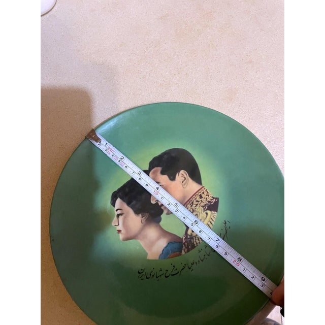 A striking vintage decorative ceramic plate featuring the royal portraits of Mohammad Reza Pahlavi and Farah Pahlavi,...