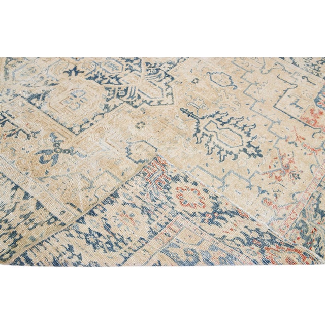 Beautiful antique Heriz hand-knotted wool rug with a beige field. This Persian rug has a blue frame and accents in a...