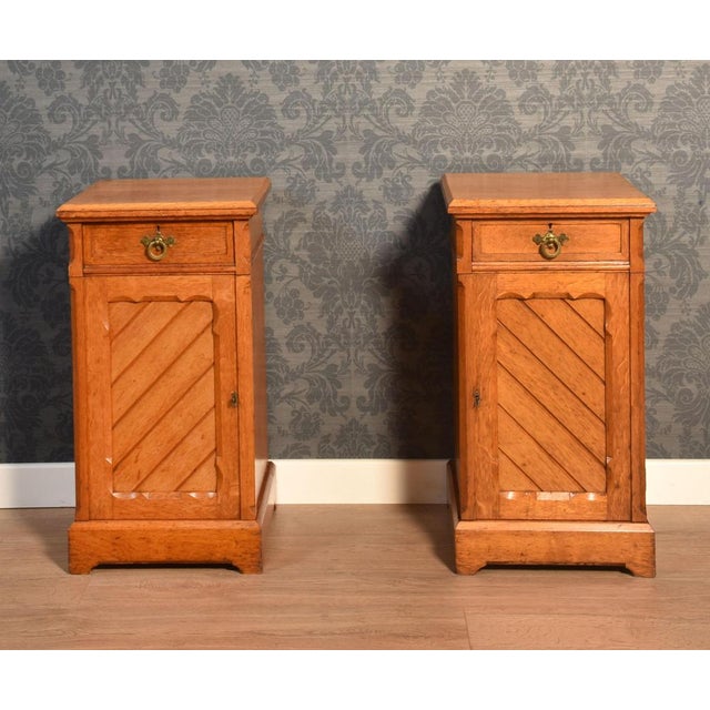 Pair of oak aesthetic period bedside Cabinets the square top to the short frieze drawer fitted with brass handle. Above...