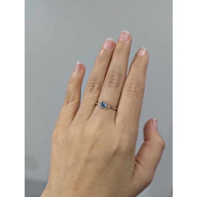 A charming dainty ring showcasing a 0.34 carat trillion aquamarine centerpiece, accented with ethically sourced earth...